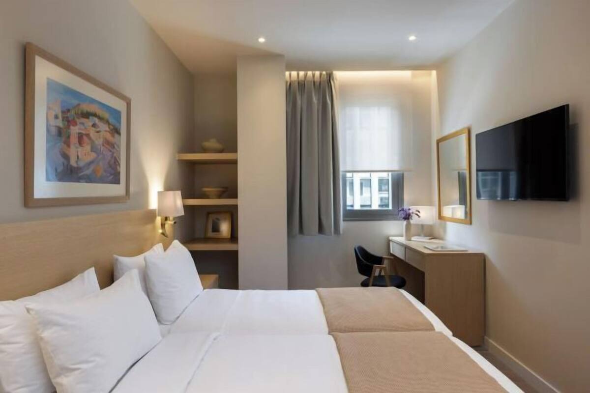 Ein Hotelzimmer mit Bett, Schreibtisch, Fernseher und einem Bild an der Wand.