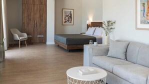 Una habitación de hotel moderna con una cama, un sofá, una silla y una mesita.