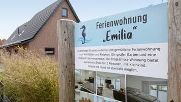 En skylt för ett modernt och bekvämt semesterhus som heter ”Emilia”, med en stor trädgård och en flyttbar solterrass.