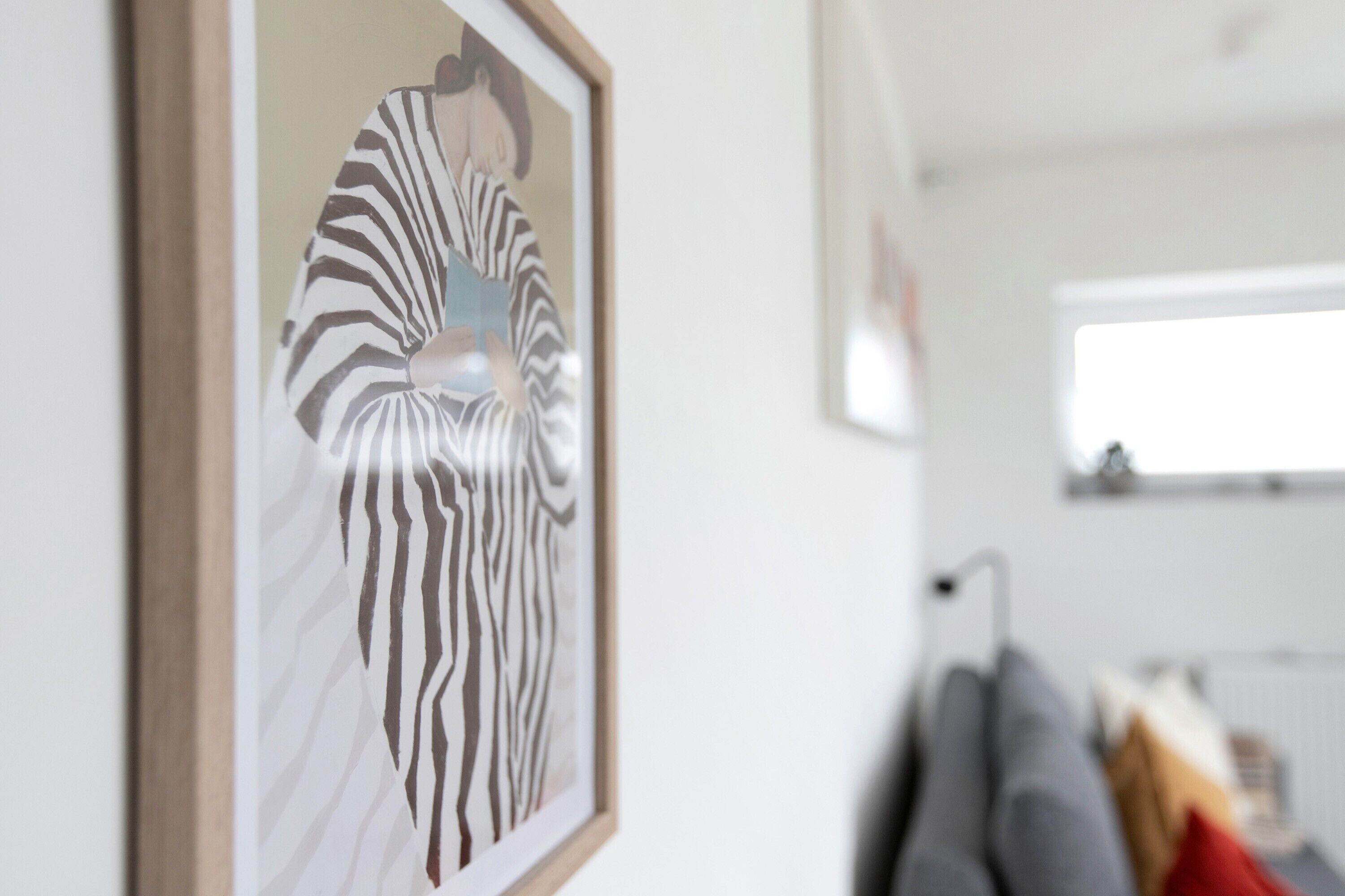 Een lijst met een zebrabeeld, een grijze bank en een raam in een kamer.