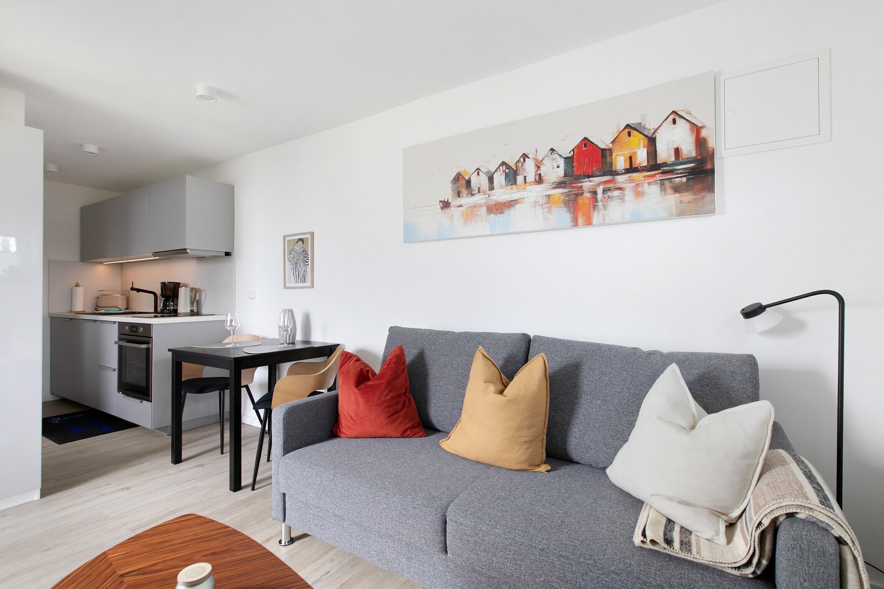 Un salon moderne avec un canapé gris, une table à manger et une cuisine en arrière-plan.