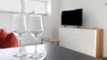 Dos copas de vino vacías sobre una mesa en una habitación con televisión y ventana.