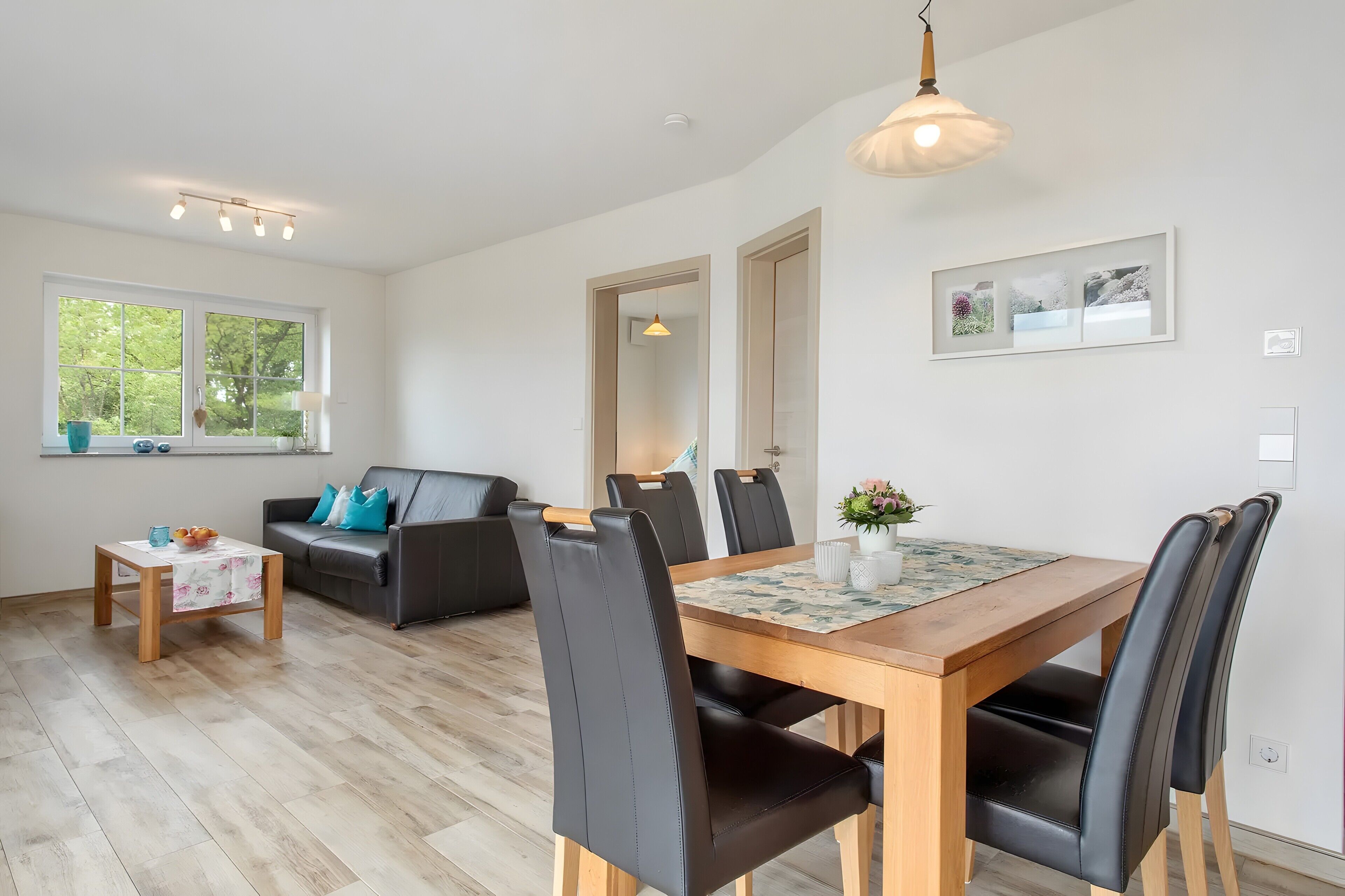 A modern living room with a dining area, a sofa, a coffee table, and a dining table with chairs.