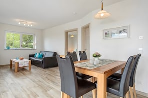Un salon moderne comprenant un coin repas, un canapé, une table basse et une table à manger avec des chaises.