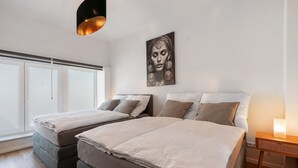 Un dormitorio con dos camas, un ventanal grande y una obra de arte colgada en la pared.