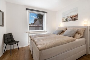 A bedroom with a bed, a chair, a window, and a wall-mounted picture. - Apartment 'In München Eg' with Shared Garden and Wi-Fi (München)