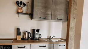 Een moderne keuken met grijze kastjes, een houten aanrecht, een koffiezetapparaat en een spoelbak.