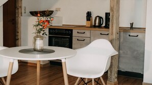 Een keuken met een witte tafel en stoelen, een fornuis en een koffiezetapparaat.