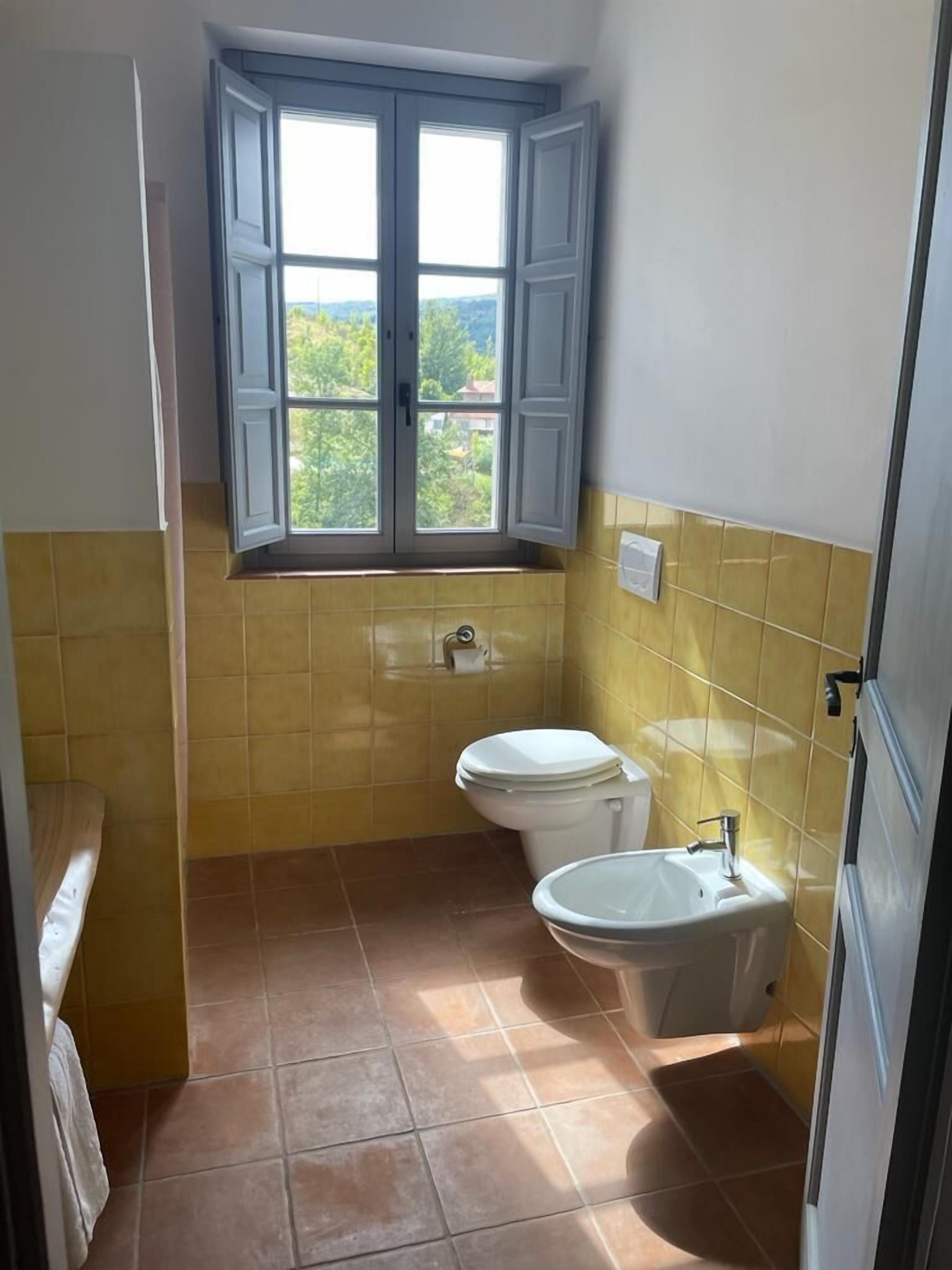 Une petite salle de bain avec une fenêtre, des toilettes et un lavabo.