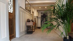 A hallway with a wooden door, a small table with decorative items, and a potted plant. - Apartment 'Ferienwohnung' with Private Terrace, Private Garden and Wi-Fi (Eslohe)