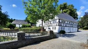 A traditional half-timbered building with a paved courtyard and a metal fence. - Apartment 'Ferienwohnung' with Private Terrace, Private Garden and Wi-Fi (Eslohe)