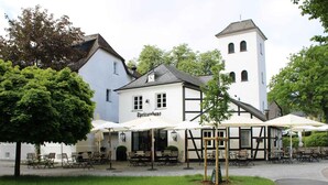 A building with outdoor seating, a sign reading 'Spritzenhaus,' and a tower. - Apartment 'Ferienwohnung' with Private Terrace, Private Garden and Wi-Fi (Eslohe)