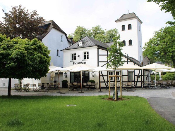 A building with outdoor seating, a sign reading 'Spritzenhaus,' and a tower.