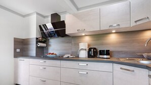 A modern kitchen with built-in cabinets, a coffee maker, and a kettle.