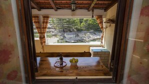A wooden table with a bottle and glasses, a bowl of lemons, and a view of a rocky landscape through a window with curtains. - House B - 45m From the Sea (Vela Luka)