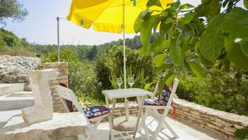 Relax in a serene outdoor seating area surrounded by lush greenery and a hilly landscape.
