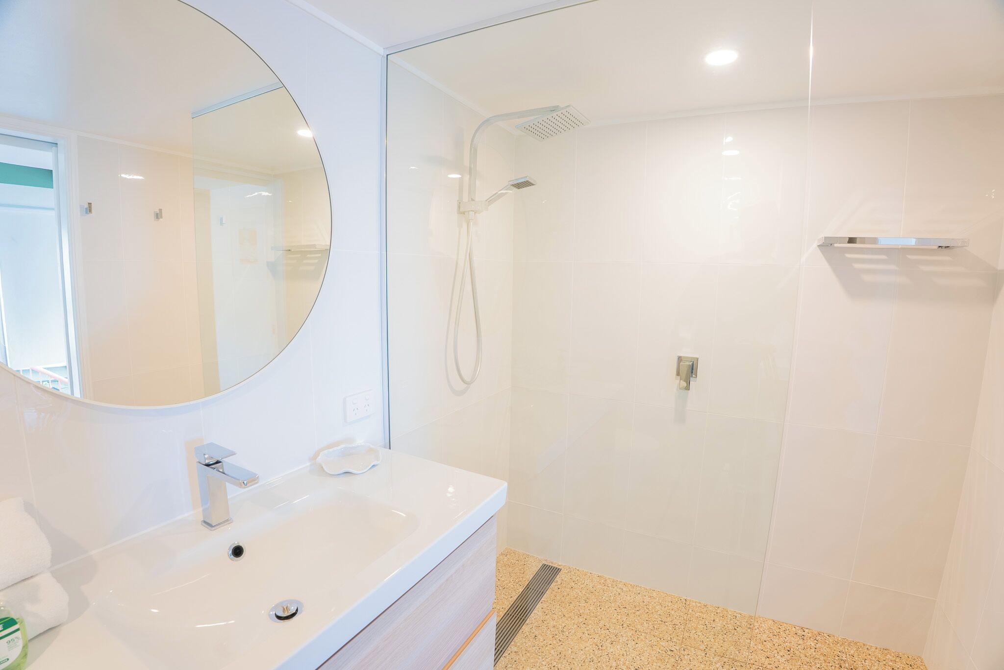 A modern bathroom with a white sink, mirror, and shower.