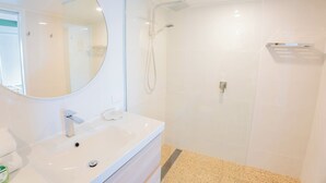 A modern bathroom with a white sink, mirror, and shower.