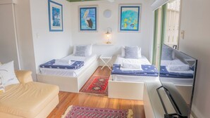 A room with two beds, a sofa, a TV, and artwork on the walls.