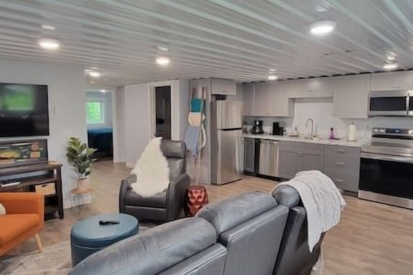 Relax in this stylish living space with a comfortable sofa, flat-screen TV, and kitchenette featuring a refrigerator and sink.