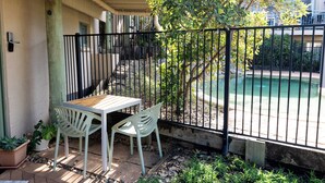 Une terrasse avec une table et des chaises, une piscine et une clôture.