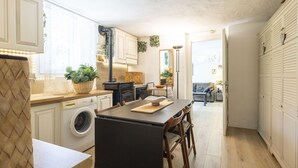 A compact kitchen with a washing machine, a dining table, and a sofa in the adjacent living area. - Il Castagneto by Interhome (Iseo)