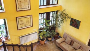 Un vaste espace de vie comprenant un canapé, des plantes en pot et des œuvres d’art accrochées aux murs.