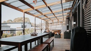 Une terrasse extérieure avec des meubles en bois, un barbecue et une vue sur les environs.