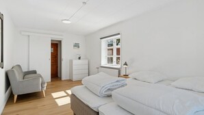A bedroom with a bed, a chair, a dresser, and a window.