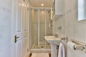 A bathroom with a glass-enclosed shower, a white sink, and a towel rack.