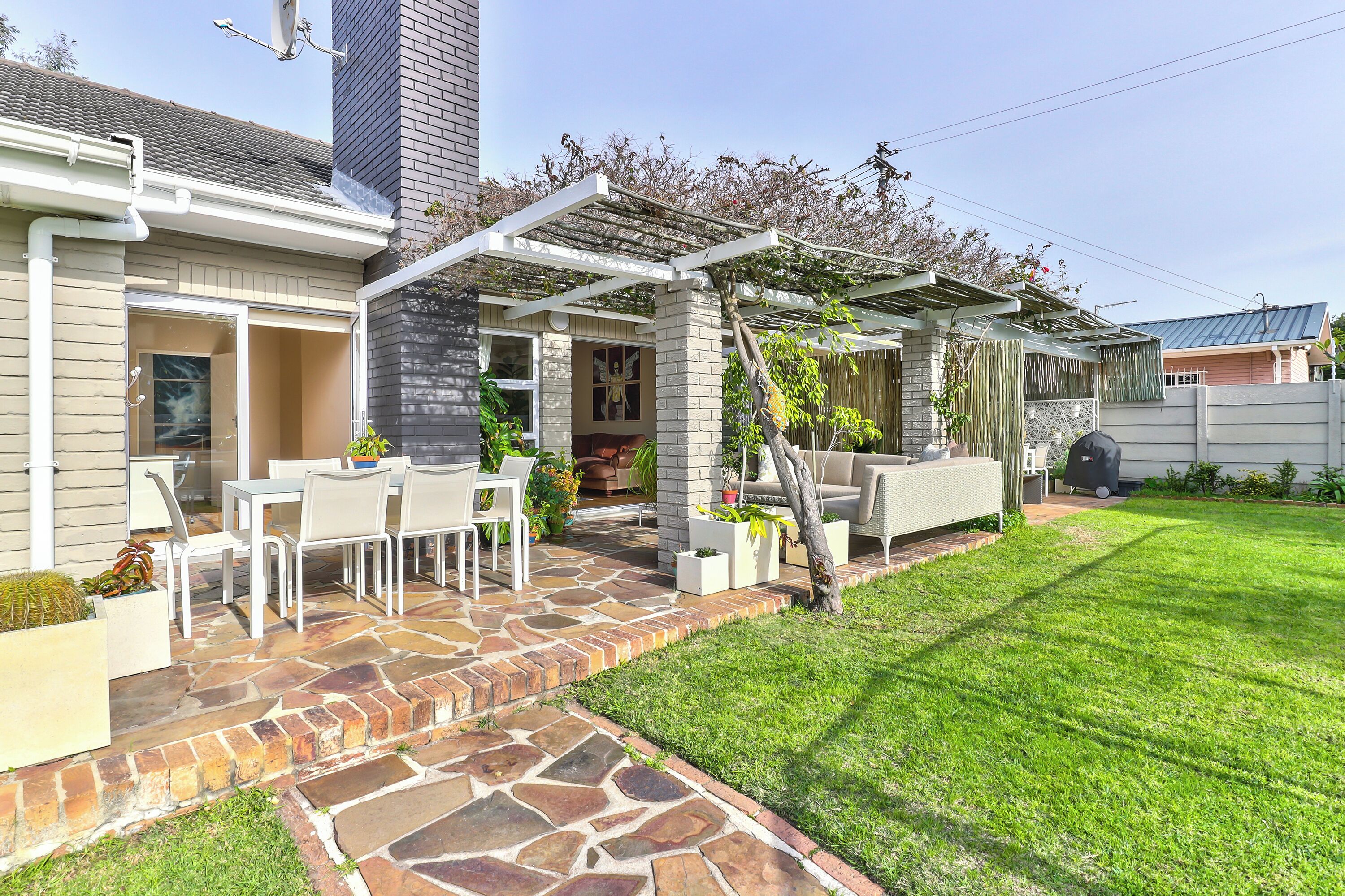 A patio area with stone flooring, outdoor furniture, and a pergola.