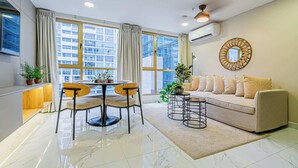 A modern living room with a round dining table, two chairs, a beige sofa, and a coffee table.