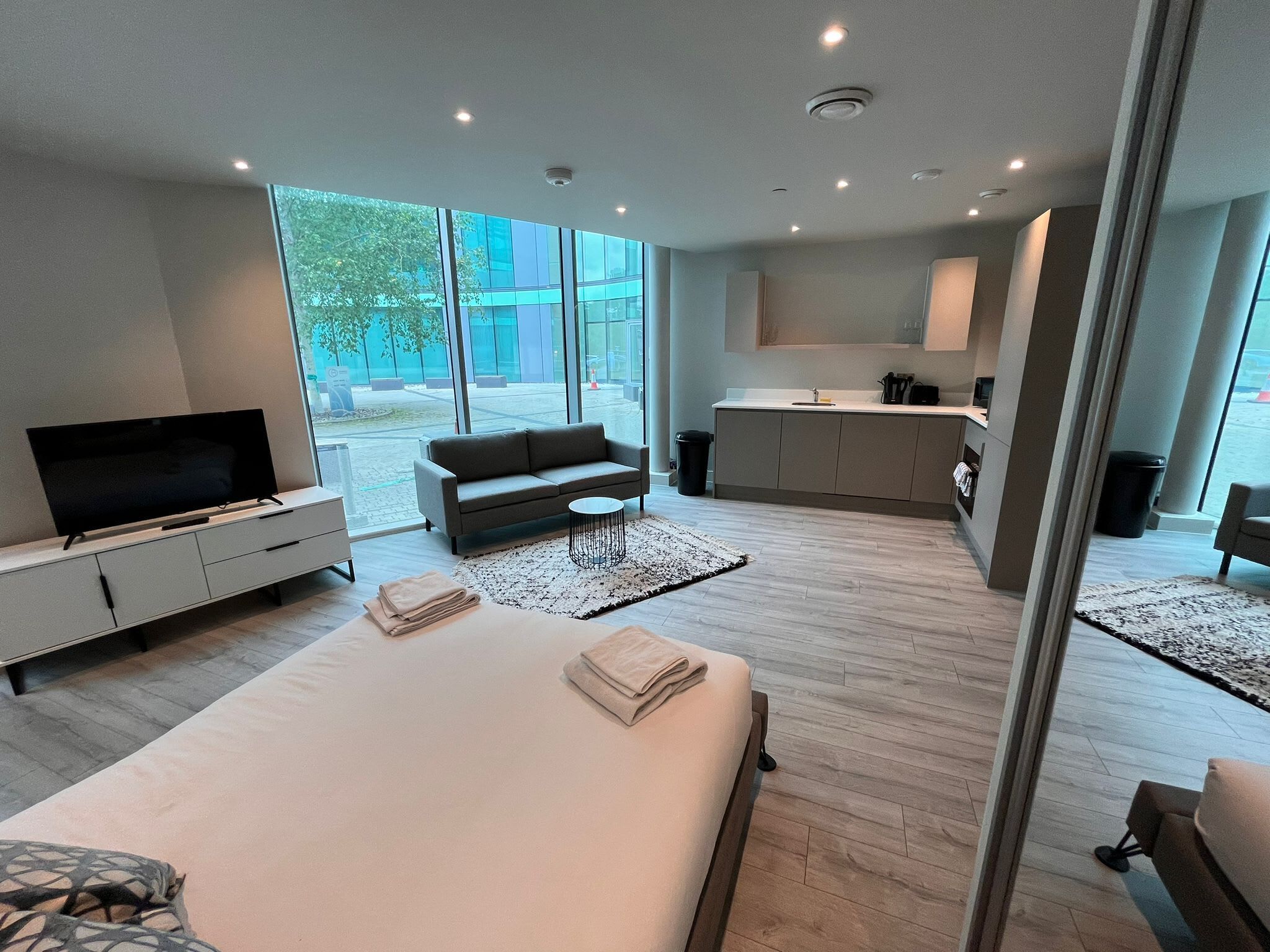 Une chambre d’hôtel moderne, dotée d’un grand lit, d’un canapé, d’une télévision et offrant une vue sur l’extérieur.