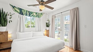 A bedroom with a large bed, a ceiling fan, and a view of a pool through the sliding glass door.