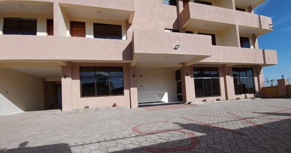 A multi-story building with a flat facade, large windows, and a paved entrance area. - Nakuru Axis Hotel (Nakuru)
