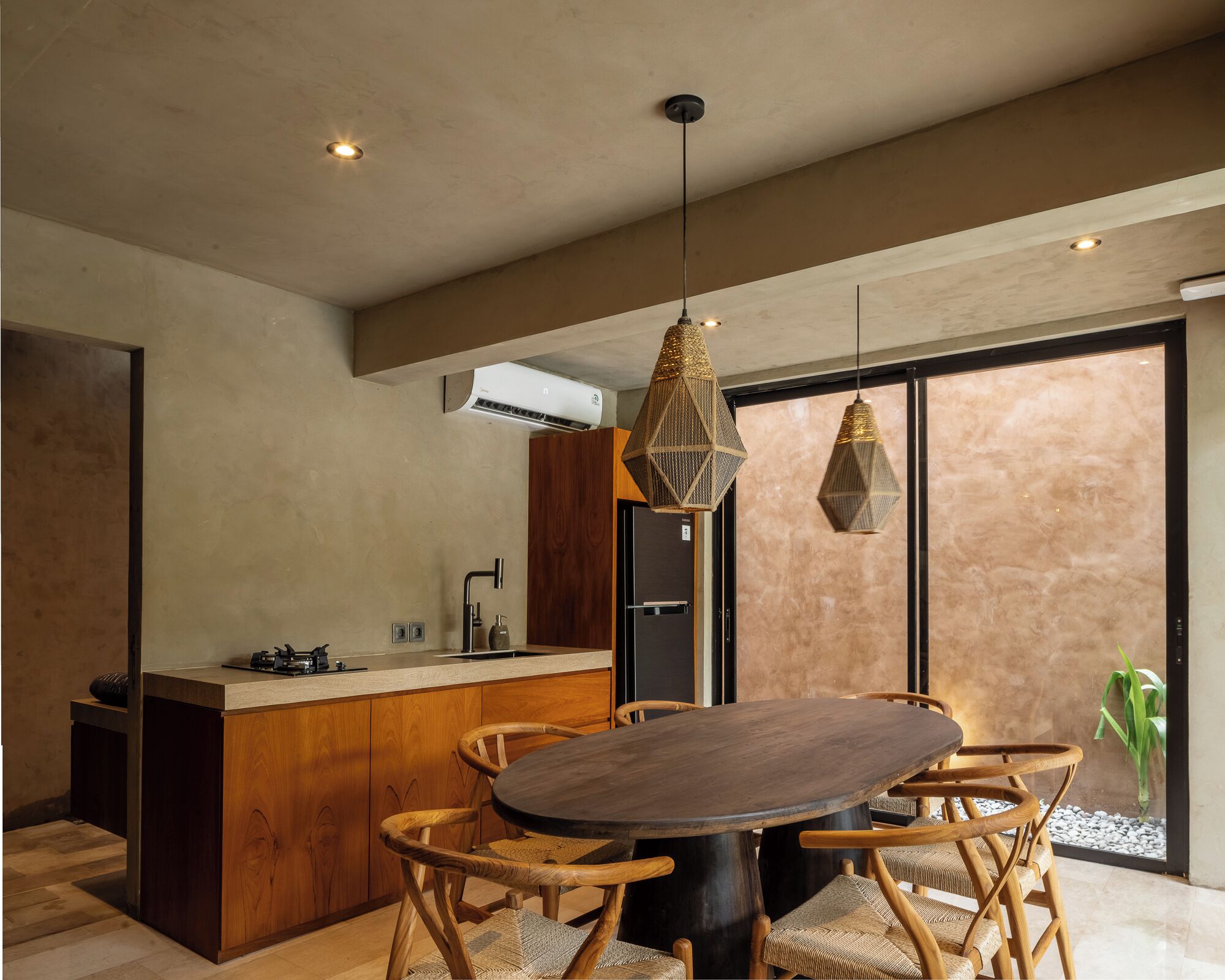 A modern kitchen with a wooden island, a dining area with a round table and chairs, and pendant lighting.
