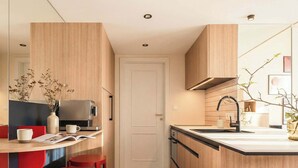 A modern kitchen with a built-in coffee machine, a sink, and red bar stools. - TurnKey | Wenceslas square Two Level Apartment III (Praha 1)