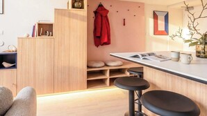 A modern kitchen with a wooden countertop, bar stools, and a red coat hanging on the wall. - TurnKey | Wenceslas square Two Level Apartment III (Praha 1)
