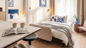 A hotel room with a bed, a desk, a chair, a mirror, and a window with curtains. - TurnKey | Wenceslas square Two Level Apartment III (Praha 1)