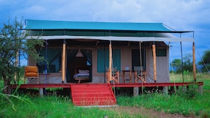 A safari tent with a red ramp, a bed, and a table with chairs. - Mlimwa Camp (Arusha)