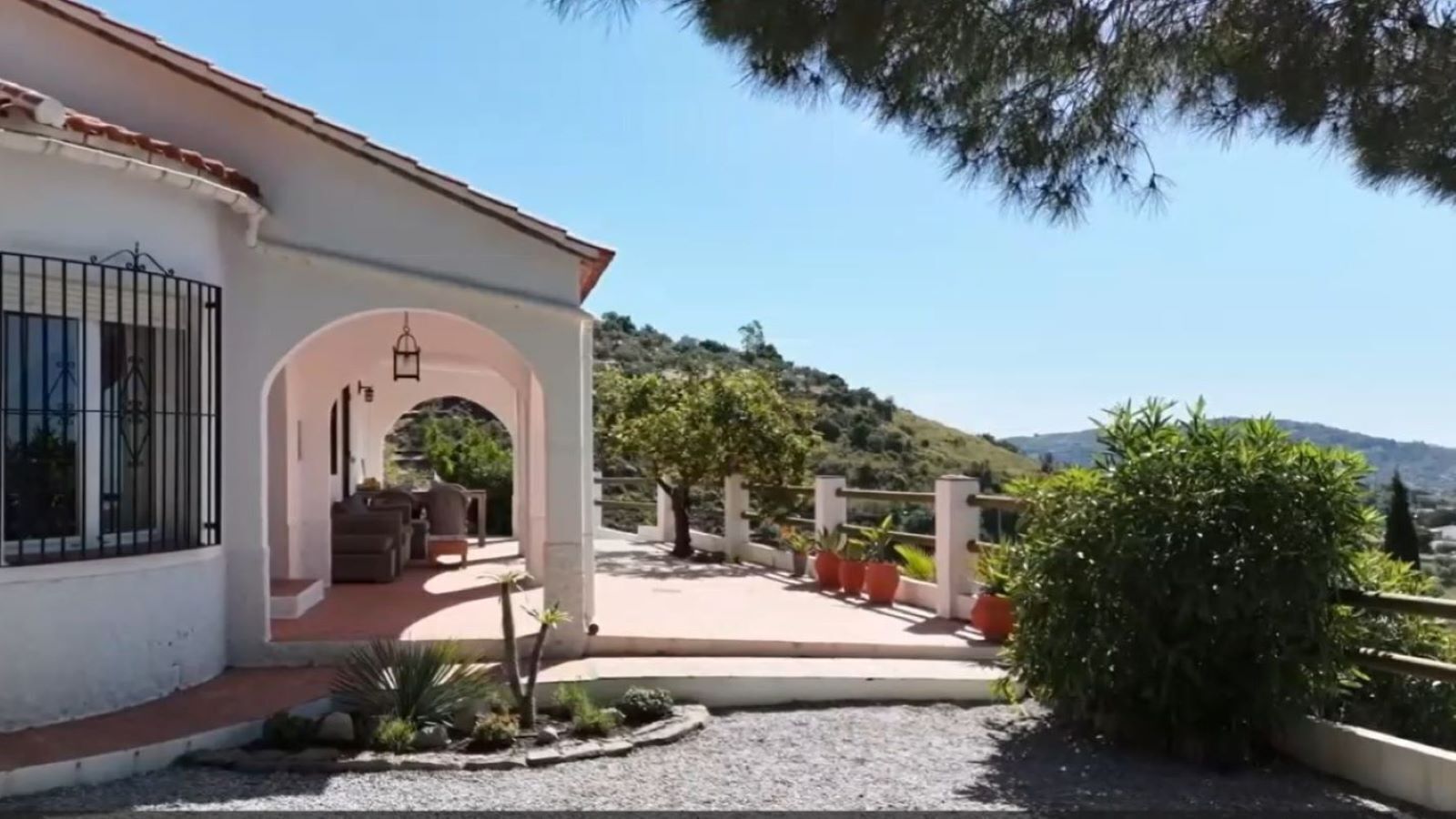 A house with a patio, outdoor furniture, and potted plants.