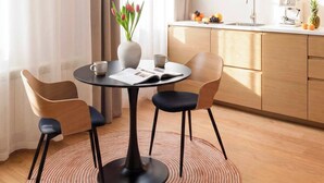 Ein moderner Essbereich mit einem runden Tisch, Stühlen, einer Blumenvase und einer Hängelampe.