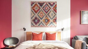 Une chambre à coucher avec un lit, des oreillers, une couverture, une décoration murale et une chaise.