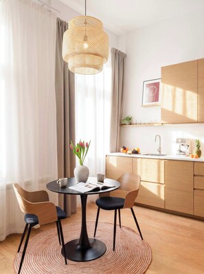 Ein moderner Essbereich mit einem runden Tisch, Stühlen, einer Blumenvase und einer Hängelampe.