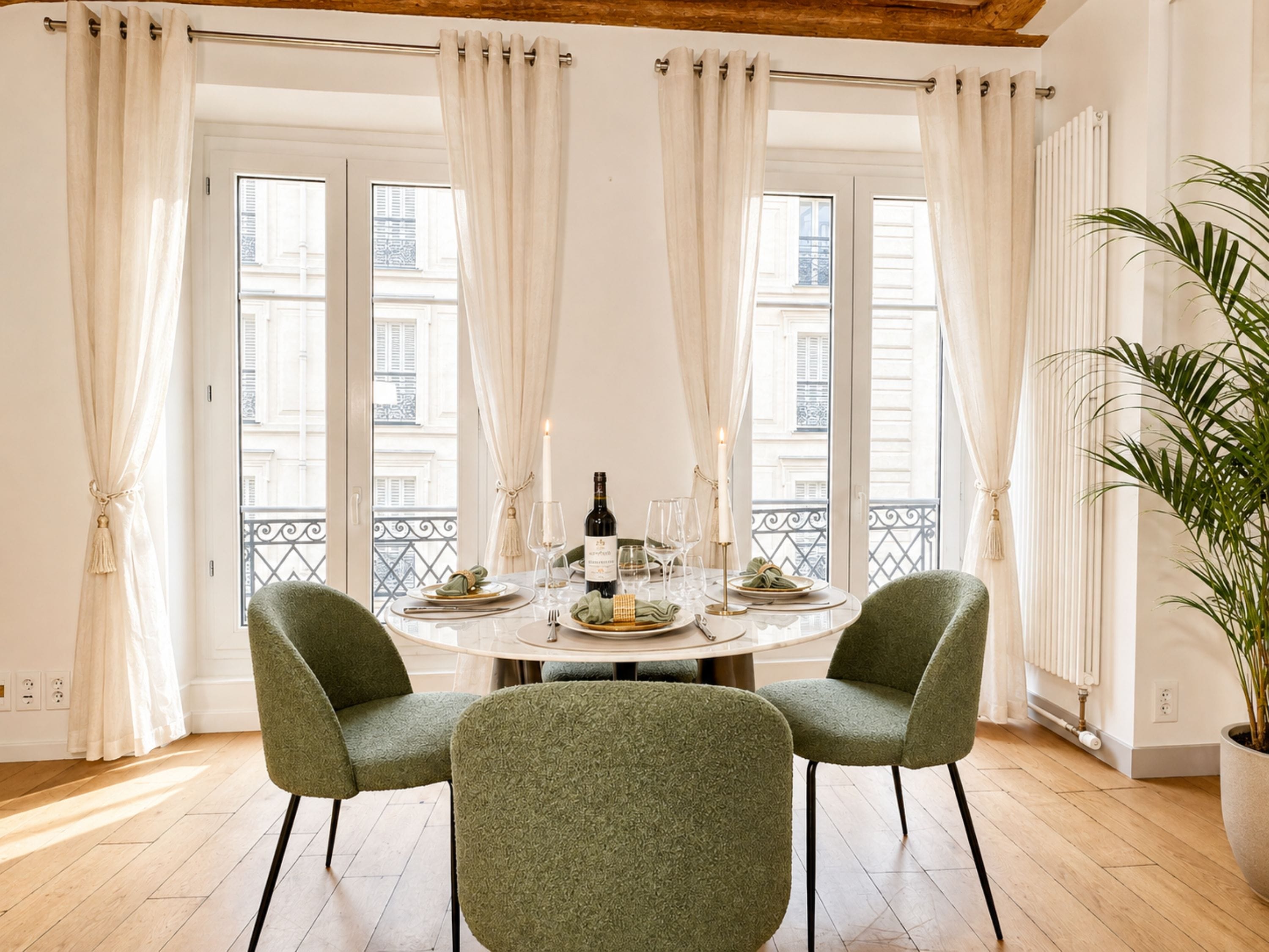 A dining area with a round table, two chairs, a candle, and a bottle of wine.