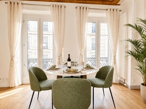 A dining area with a round table, two chairs, a candle, and a bottle of wine. - 1550 Nazareth (Paris)