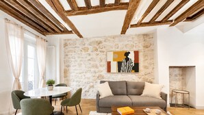 A living room with a stone wall, a sofa, a coffee table, and a fireplace. - 1550 Nazareth (Paris)