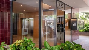 A modern building entrance with a glass door, a wooden panel wall, and a number 420 sign.