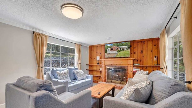 A cozy living room with a fireplace, grey sofas, and a coffee table. - Stay Roanoke | Cute 3BR Near Blue Ridge Parkway (Roanoke)
