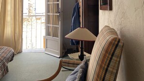 Una habitación con cama, una silla, una lámpara, un armario y una puerta que da a un balcón.